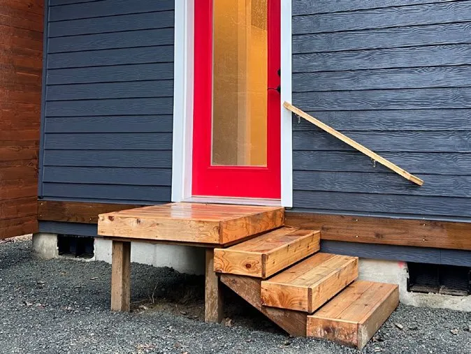 Small cedar deck with stairs at a red door