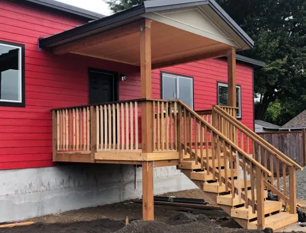 Gable-roof covered porch with stairs on a red Wolf home