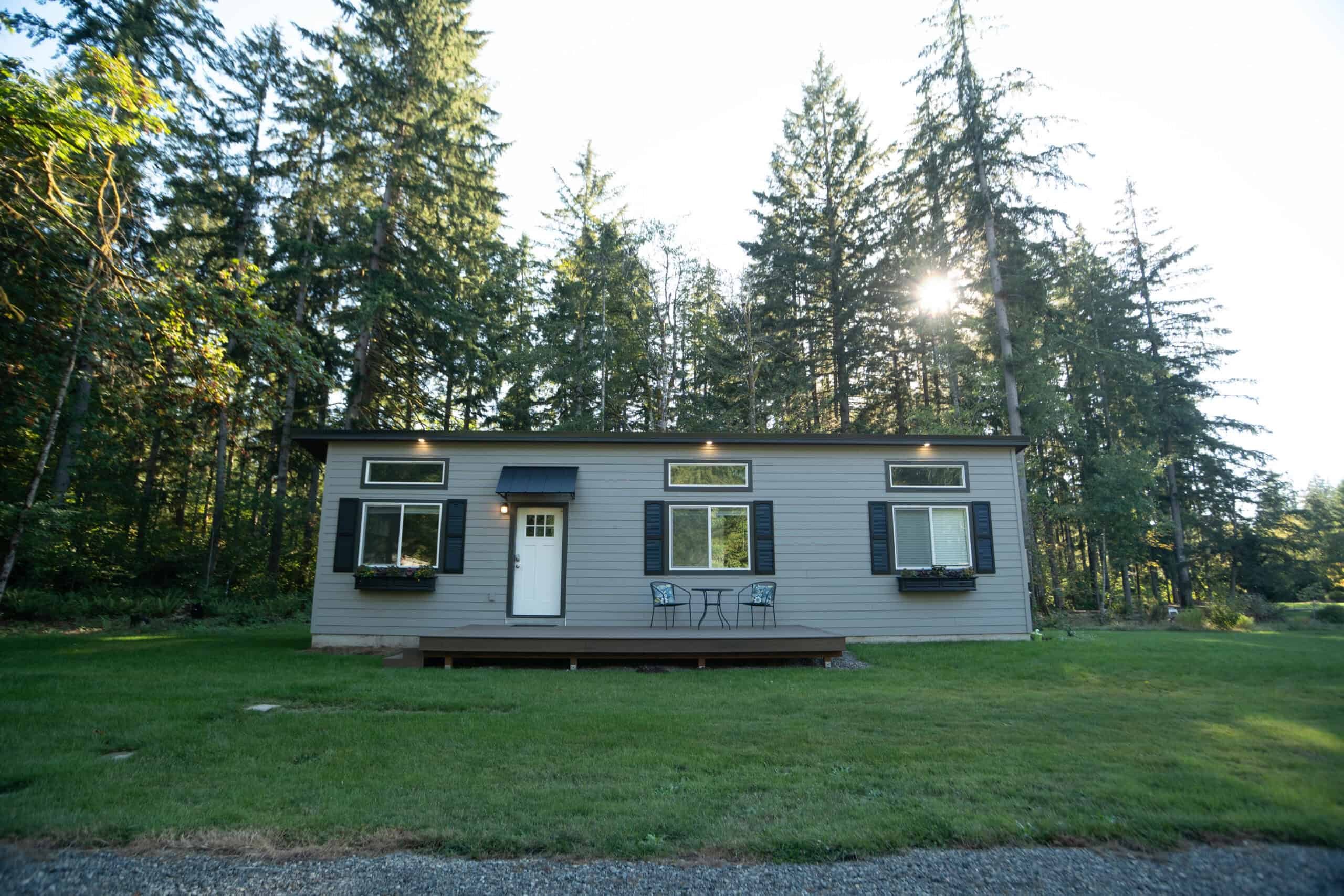 Finished Wolf modular home beside a lawn and evergreen trees