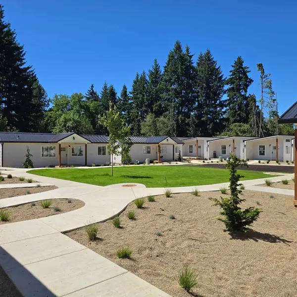 Finished white cottages with dark metal roofs around a central lawn