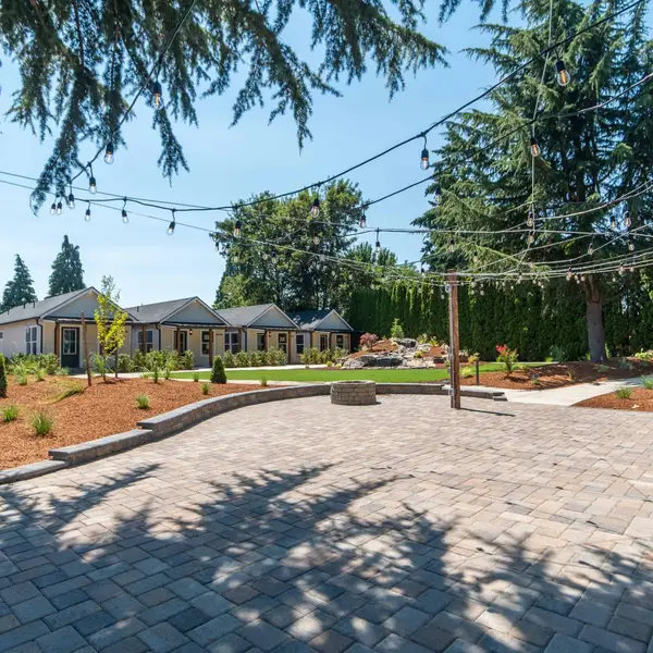 Finished beige cottages facing a brick-paved courtyard with string lights