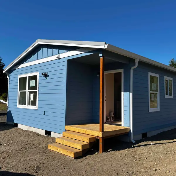 Light-blue gable Wolf Model J with a small raw-wood entry porch