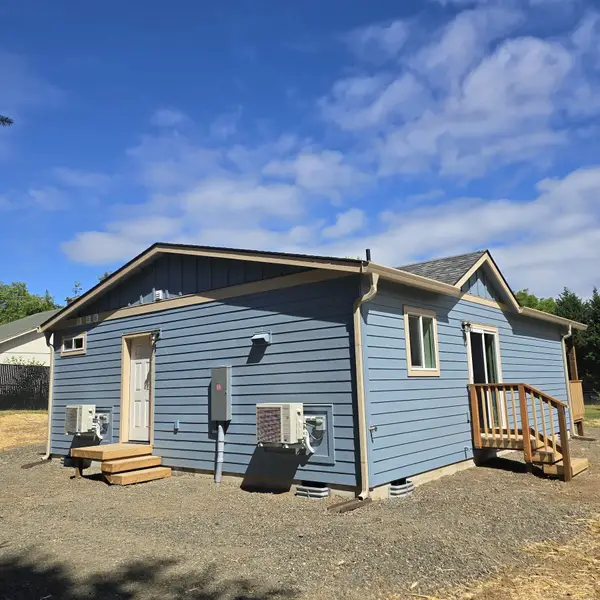 Corner of a light-blue Wolf Model L with a wall-mounted heat pump beside the sliding-door wood deck