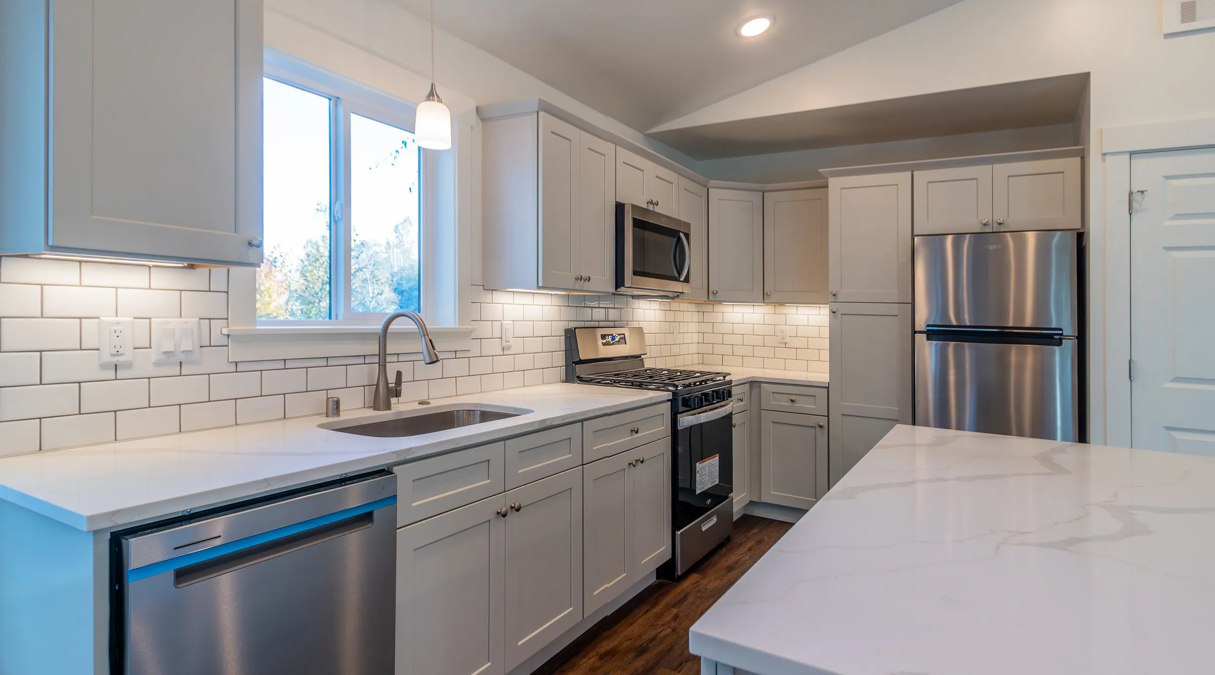 Model J kitchen with gray Shaker cabinets, quartz counters, and subway tile
