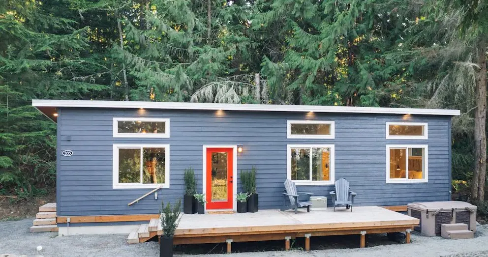Model E with blue lap siding, a red full-lite door, and a wide deck