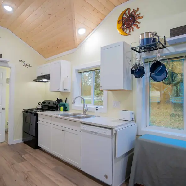 Small kitchen with a wood vaulted ceiling, white cabinets, and a window in a Wolf Model B