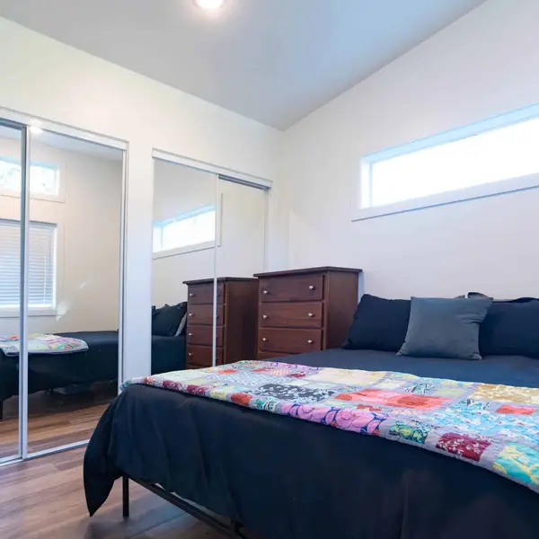 Bedroom with a dark bed, a quilt, and mirrored closet doors in a Wolf Model F