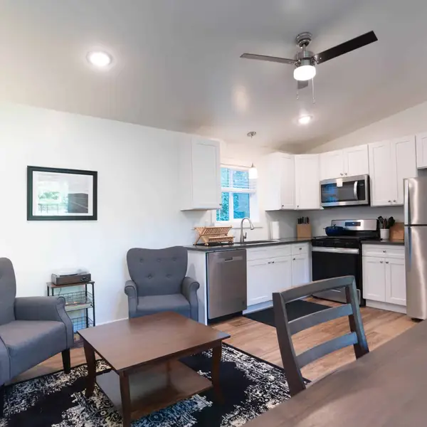 Living room and kitchen with gray armchairs and white cabinets in a Wolf Model F