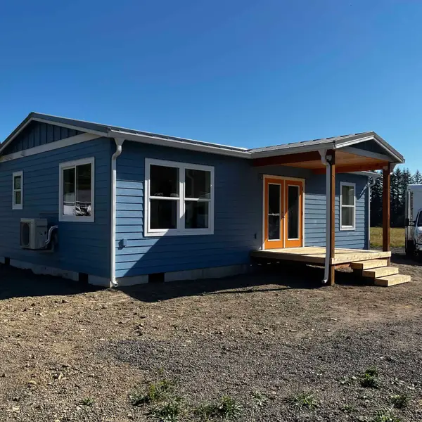Light-blue Wolf Model J with a covered wood porch and orange double doors
