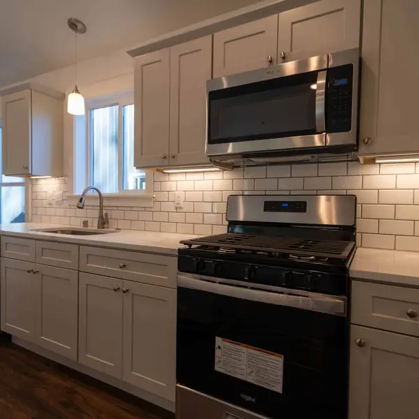 Kitchen cooking wall with light gray cabinets, a black range, and subway tile in a Wolf Model J
