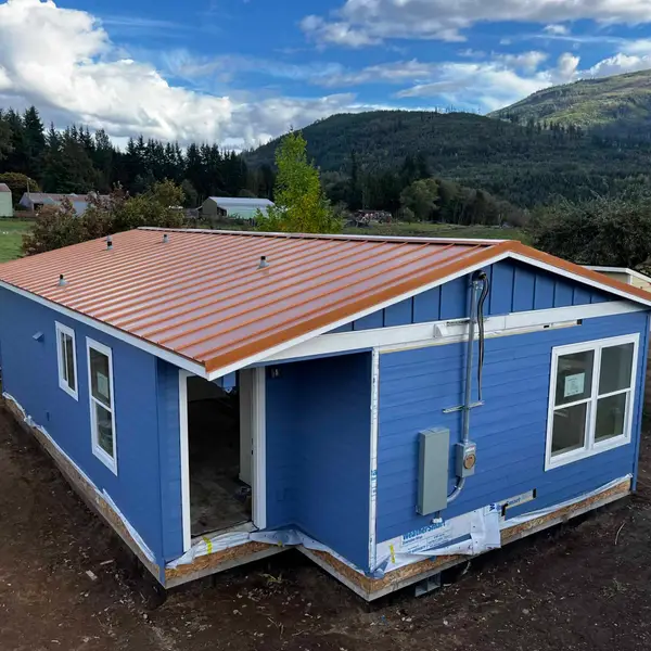 Blue Wolf Model J with a copper-colored metal roof, set on a foundation in a dirt yard