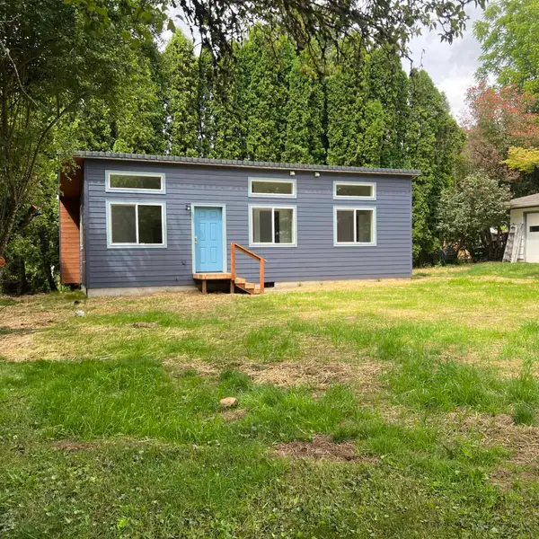 Blue-gray Wolf Model K with a light blue door and a short wood stoop on a grassy lot