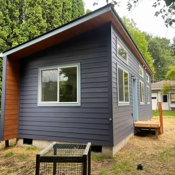 Corner of a dark blue Wolf Model K with a wood soffit and pale blue window trim
