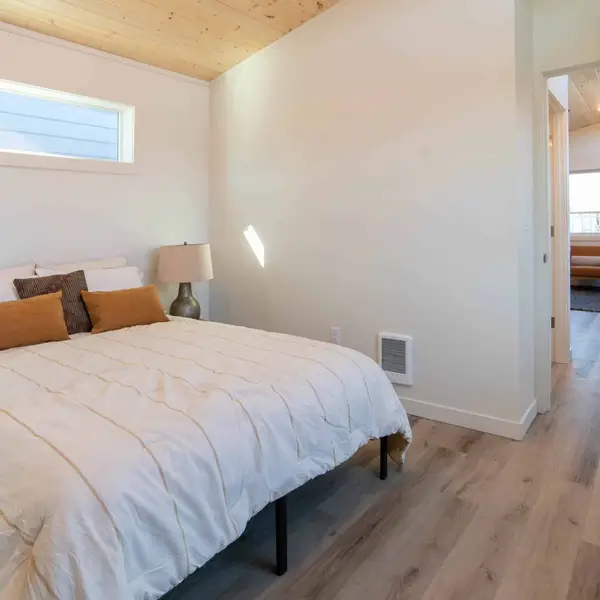 Bedroom with a wood-plank ceiling and a high window in a Wolf Model K