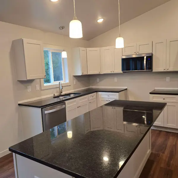 Black stone kitchen island with white cabinets in a Wolf Model L