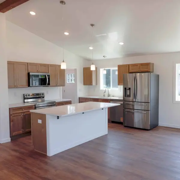 Open kitchen with light wood cabinets, a white island, and pendant lights