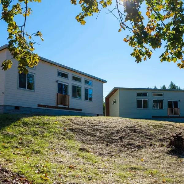 Two finished gable Wolf homes, one cream and one sage, on a grassy hillside