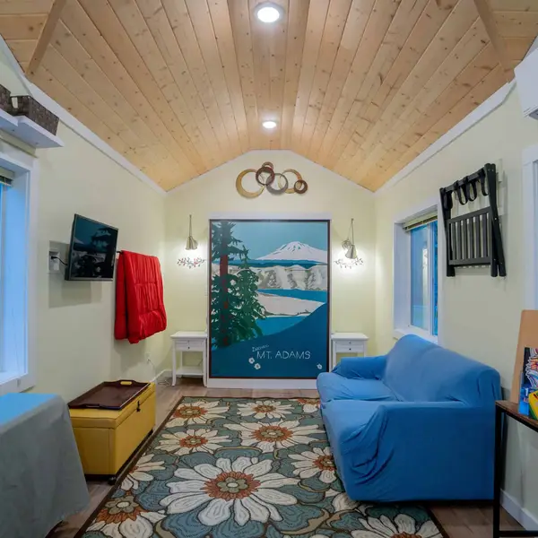 Living area with a wood vaulted ceiling, blue sofa, and a mountain mural in a Wolf Model B