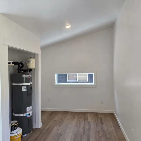 Empty room with a high window and a closet holding a water heater in a Wolf Model B