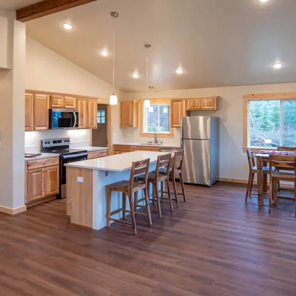Open kitchen and dining area with light wood cabinets and a white island in a Wolf Model I