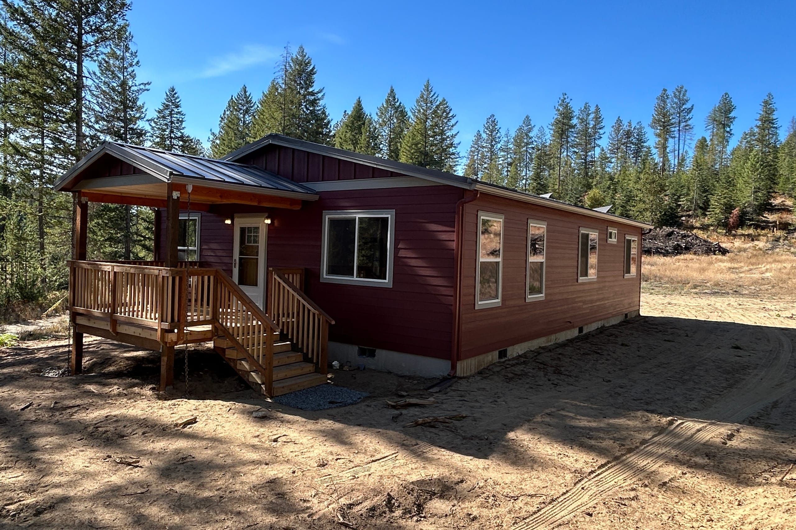 Wolf Home, a red house with a covered front porch and cedar stairs among tall pines