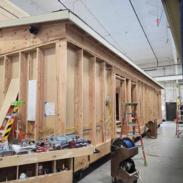 Open framing of a Wolf module in the factory, with an electrical panel on the wall