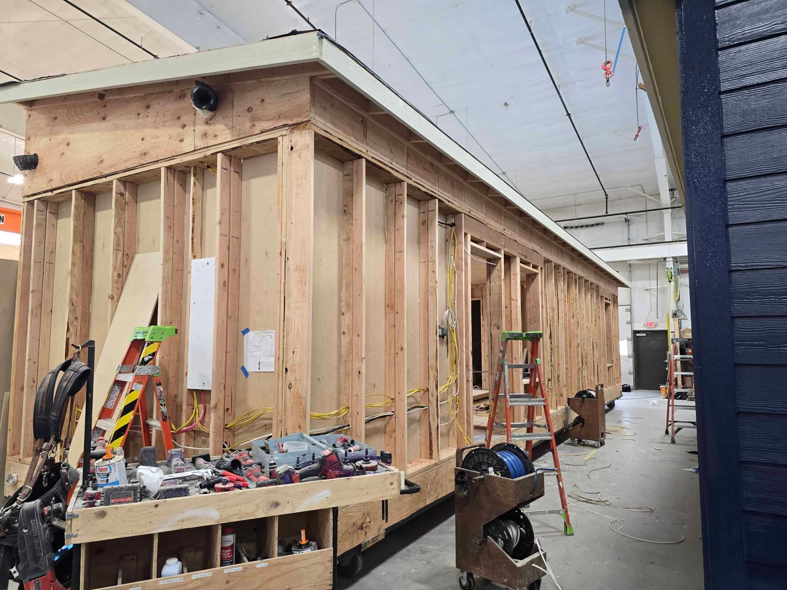 Open framing of a Wolf module in the factory, with an electrical panel on the wall