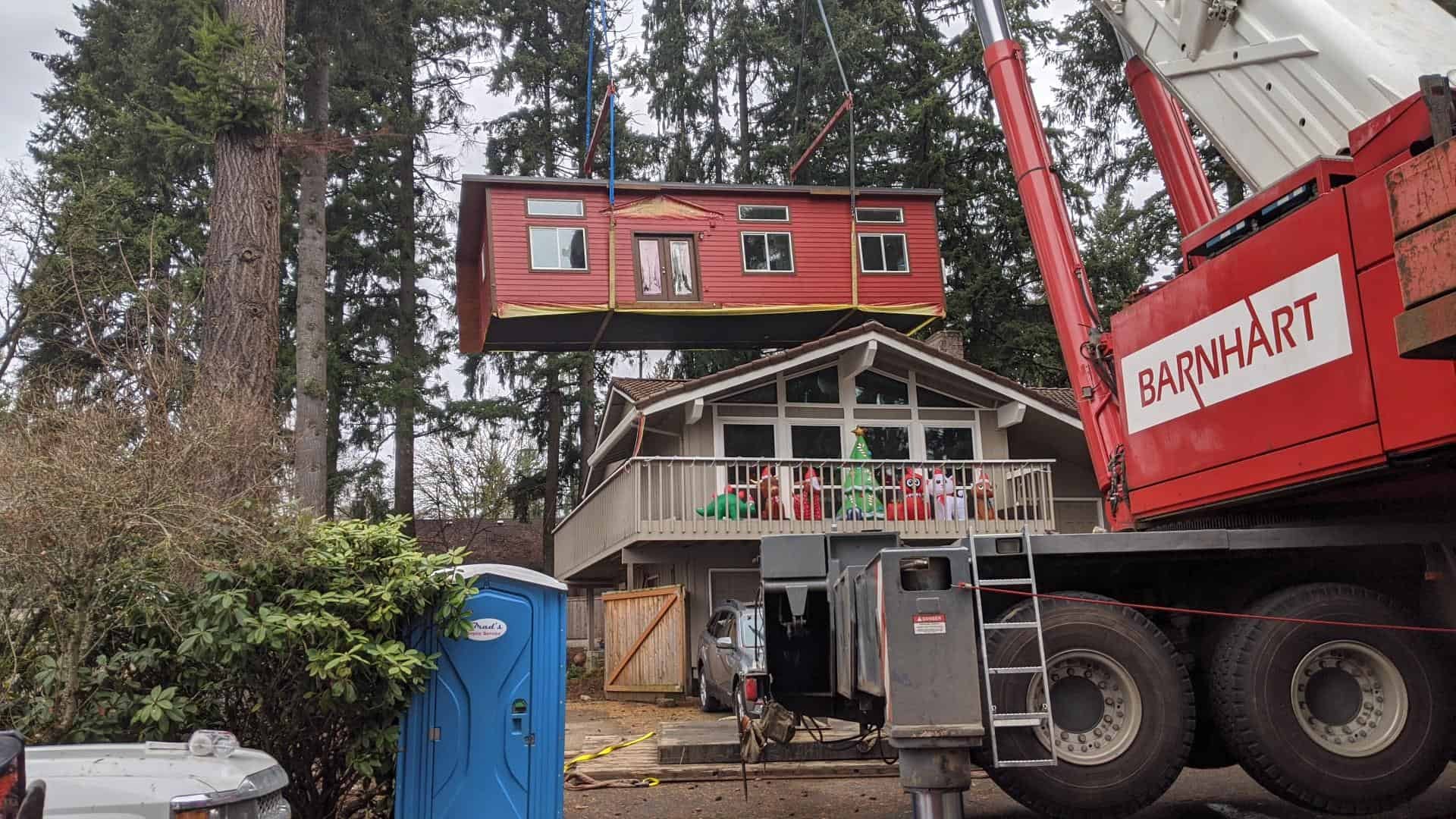 A Wolf Industries crane setting a factory-built home onto its foundation on delivery day