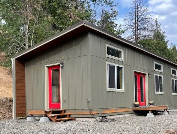 Gray-green Wolf home with white trim and a red door