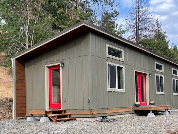 Gray-green Wolf home with white trim and a red door