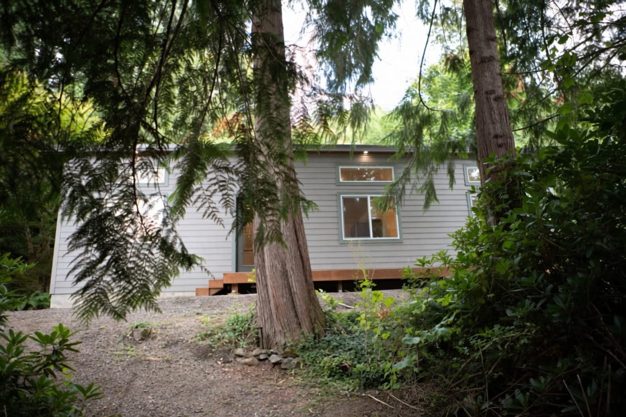 Gray Wolf Model E home with transom windows seen through trees.