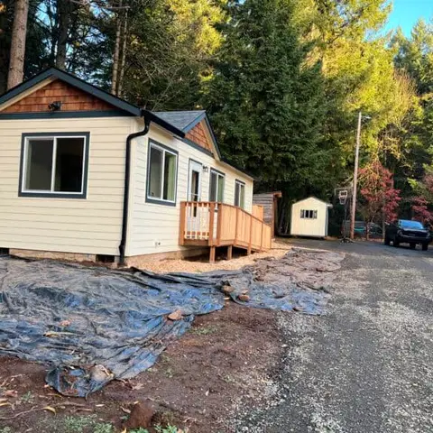Cream Wolf Model K home with black trim, a cedar-shake gable, and a wood deck.