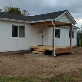 All-white Wolf Model E home with covered front deck porch.