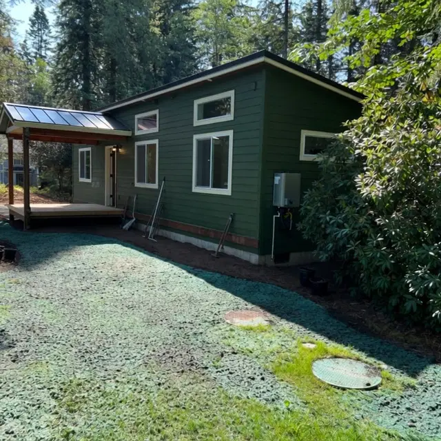 Green and white Wolf Model E home with a covered front porch deck.