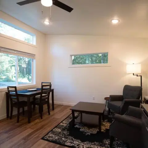 Living and dining area with transom windows and gray chairs in a Wolf Model E home.