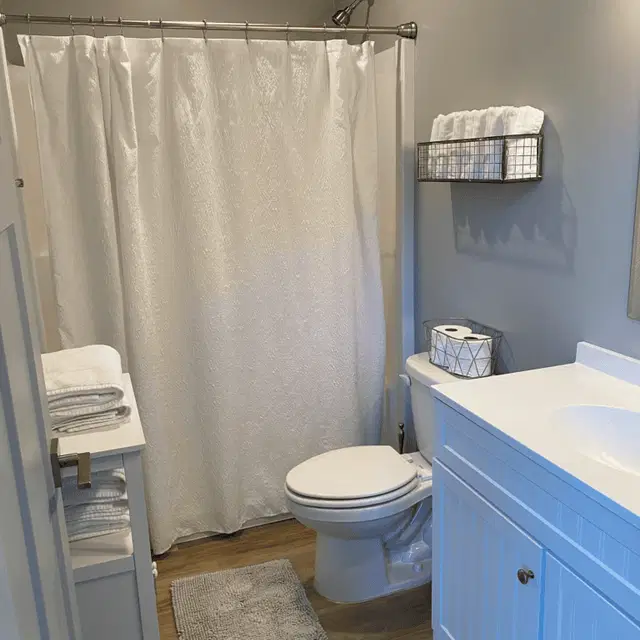 Bathroom with a shower curtain, toilet, and white vanity in a Wolf home.