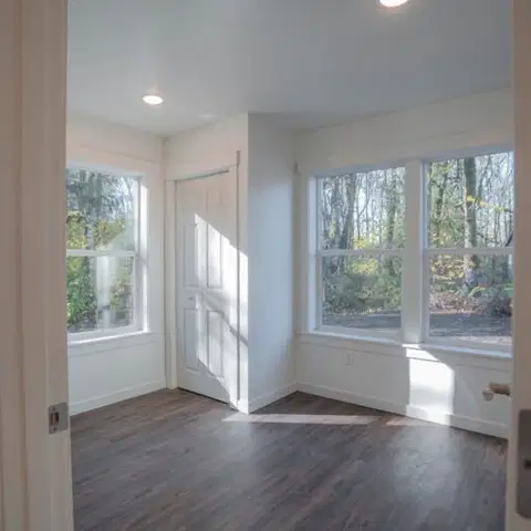 Empty room with dark flooring and windows looking into trees in a Wolf Model J home.