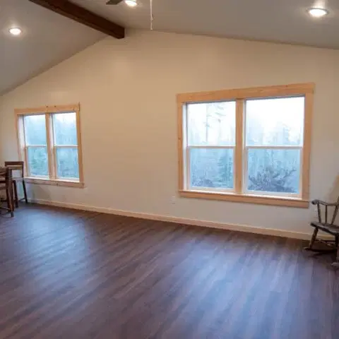 Vaulted living and dining room with a wood dining set and a rocking chair in a Wolf Model I home.