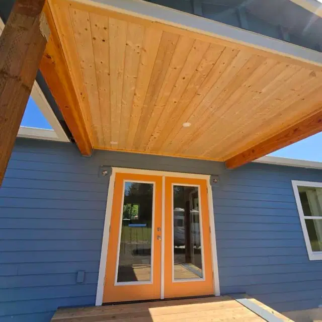 Orange French doors under a wood porch ceiling on a blue Wolf Model J home.