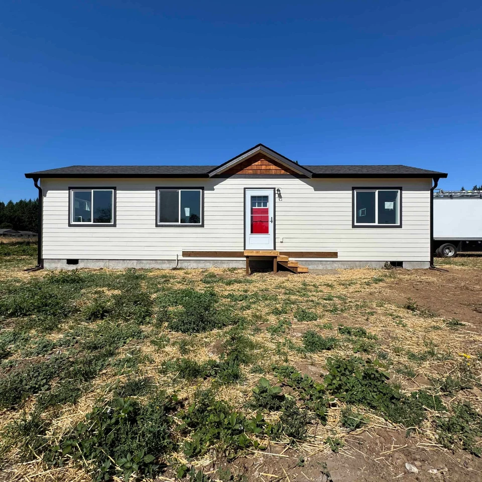White and black Wolf Model E home with red door and cedar shake gable.