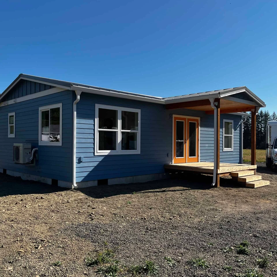 Blue and white Wold Model J modular home with orange French doors.