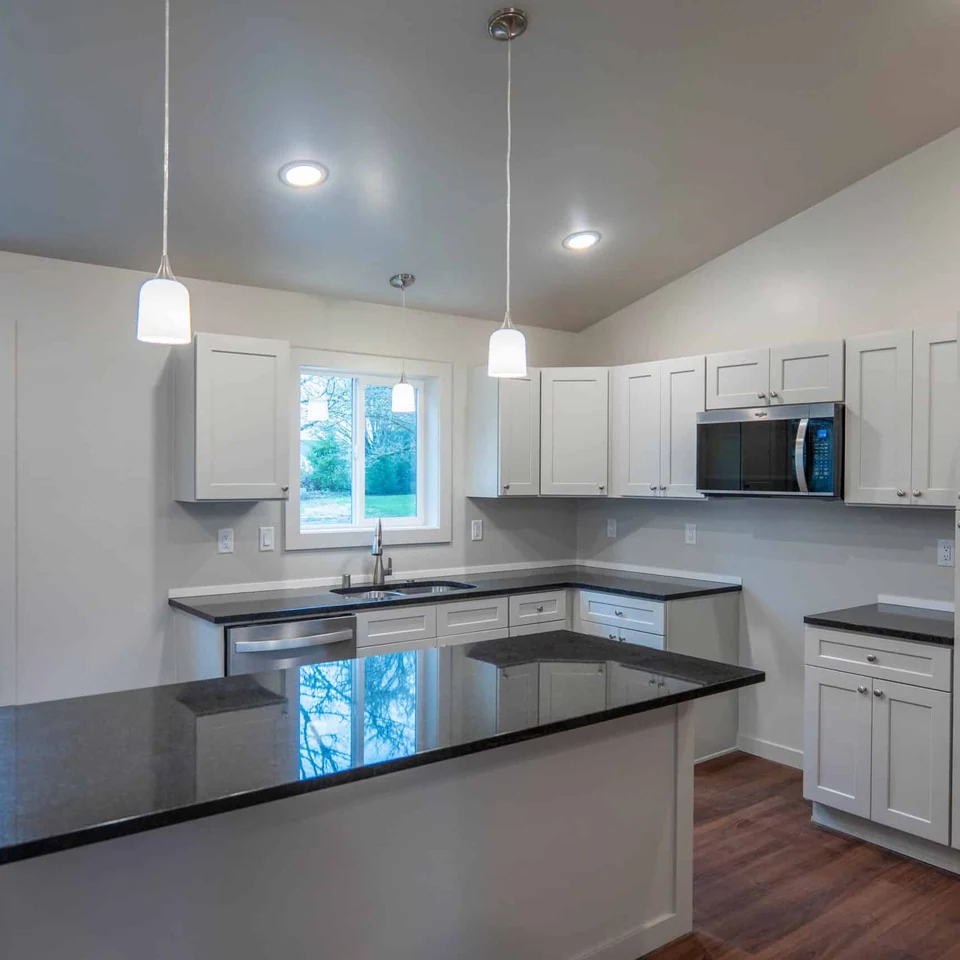 Island kitchen with black quartz countertops in a Wolf Model L home.
