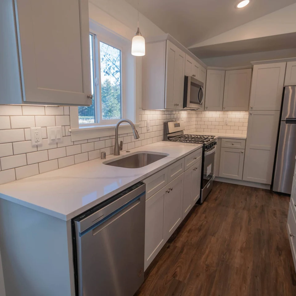 Kitchen in a Wolf Model J home with tile backsplash, island, and undermount sink.