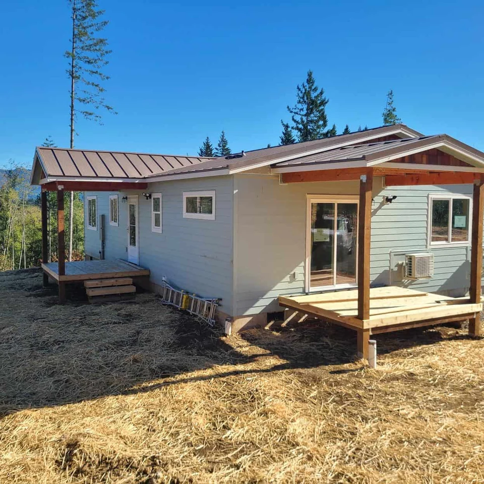 Green and white Wolf Model I home with dual covered patio decks and cedar shake gables.