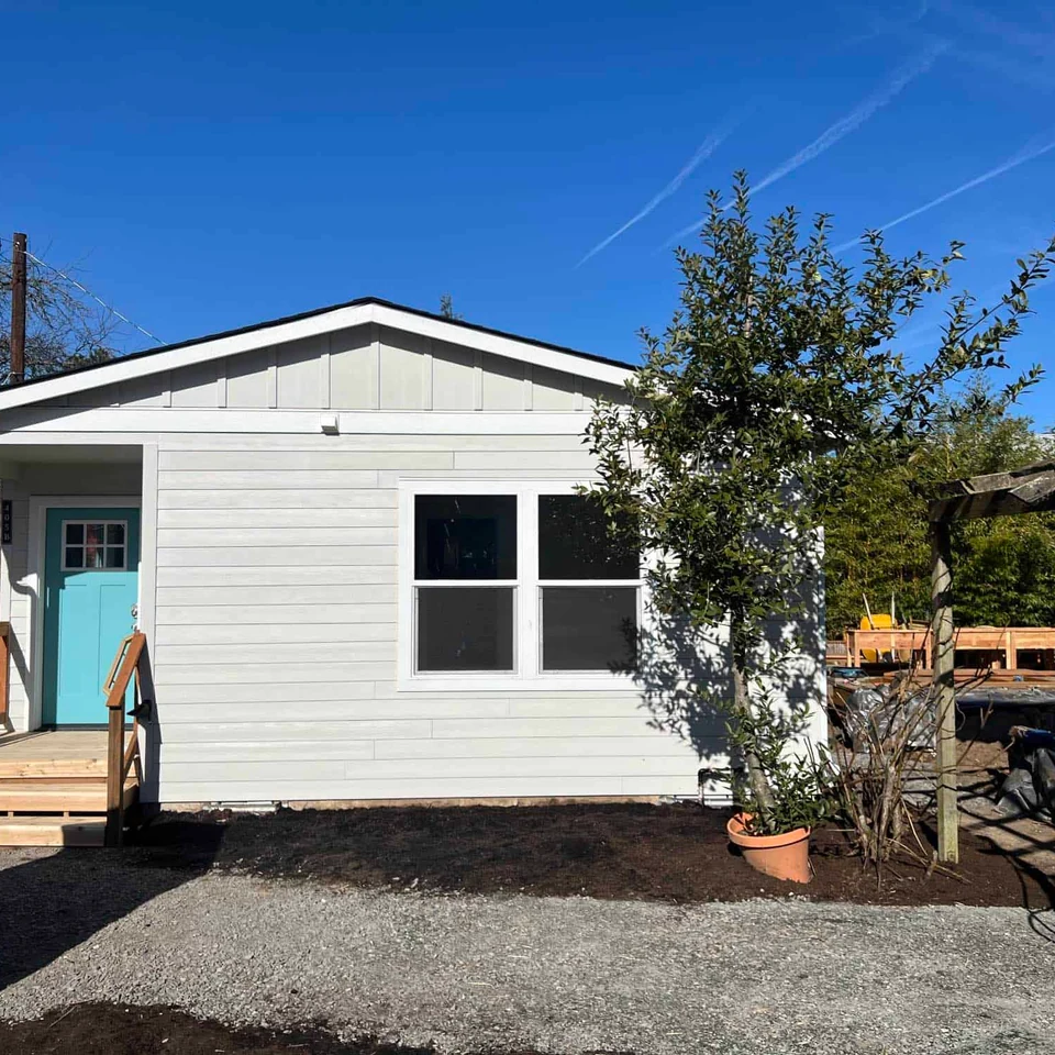 Off-white and white Wolf Model J home with baby blue front door.