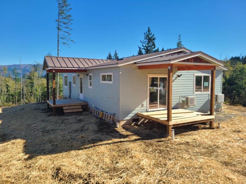Green and white Wolf Model I home with dual covered patio decks and cedar shake gables.