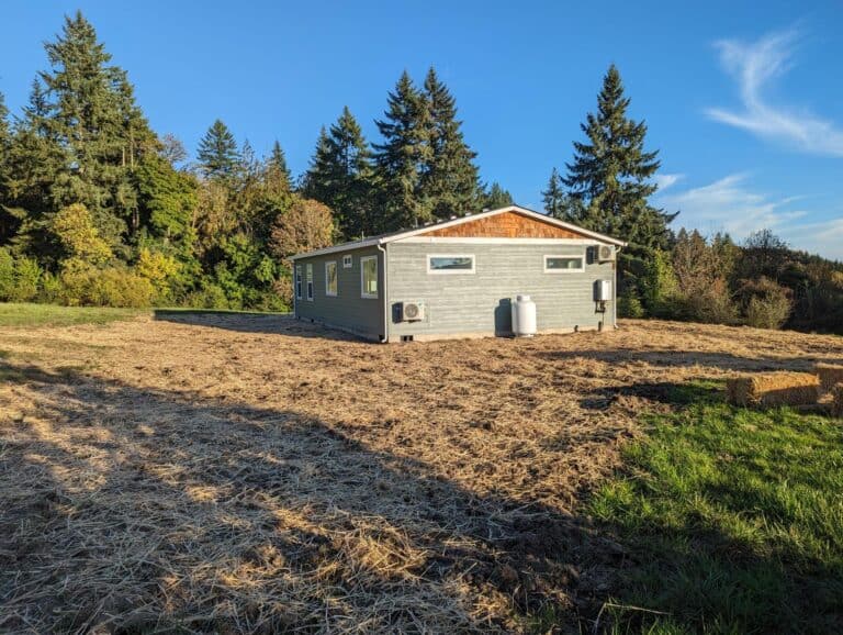 Gray Wolf Model I home with a cedar-shake gable in a field of evergreens.