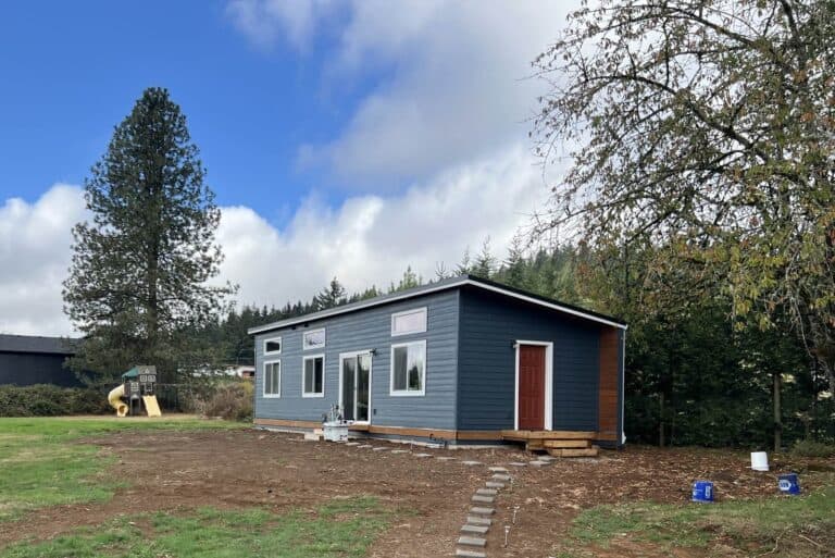 Dark blue Wolf Model E home with red door.