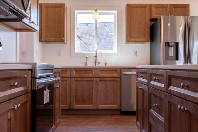 Wood kitchen with a stainless refrigerator and a window over the sink in a Wolf Model I home.