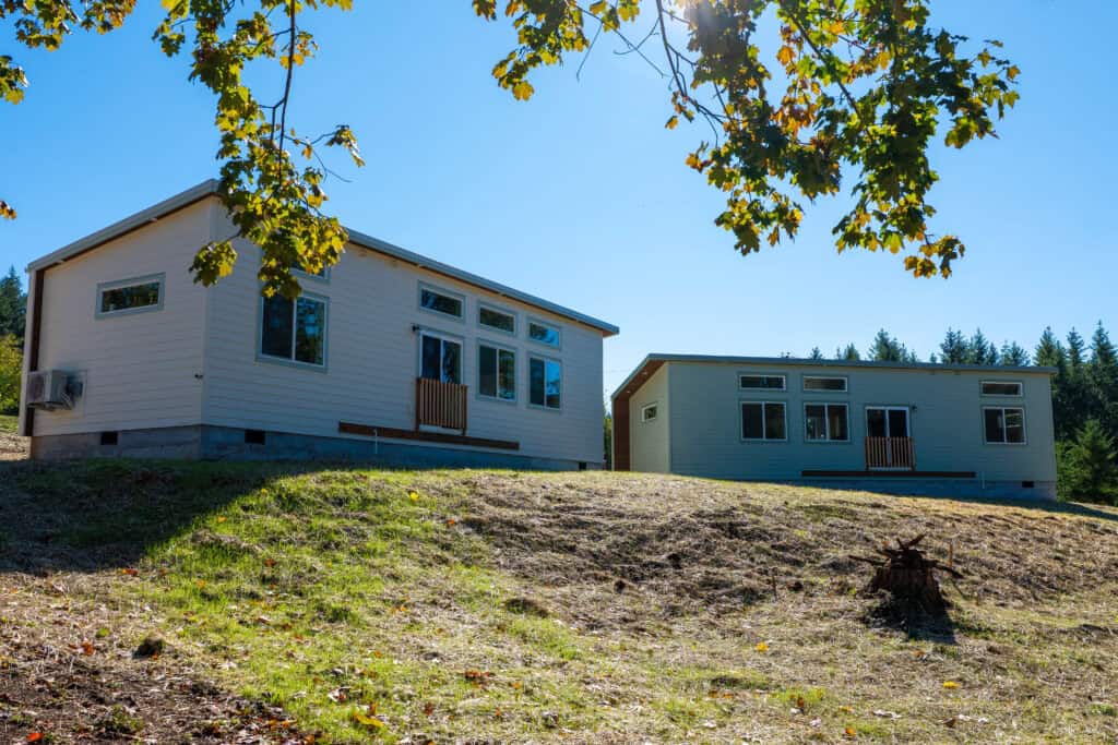 Two Wolf Model E homes on the same property set at a 90-degree angle at the top of a slope.